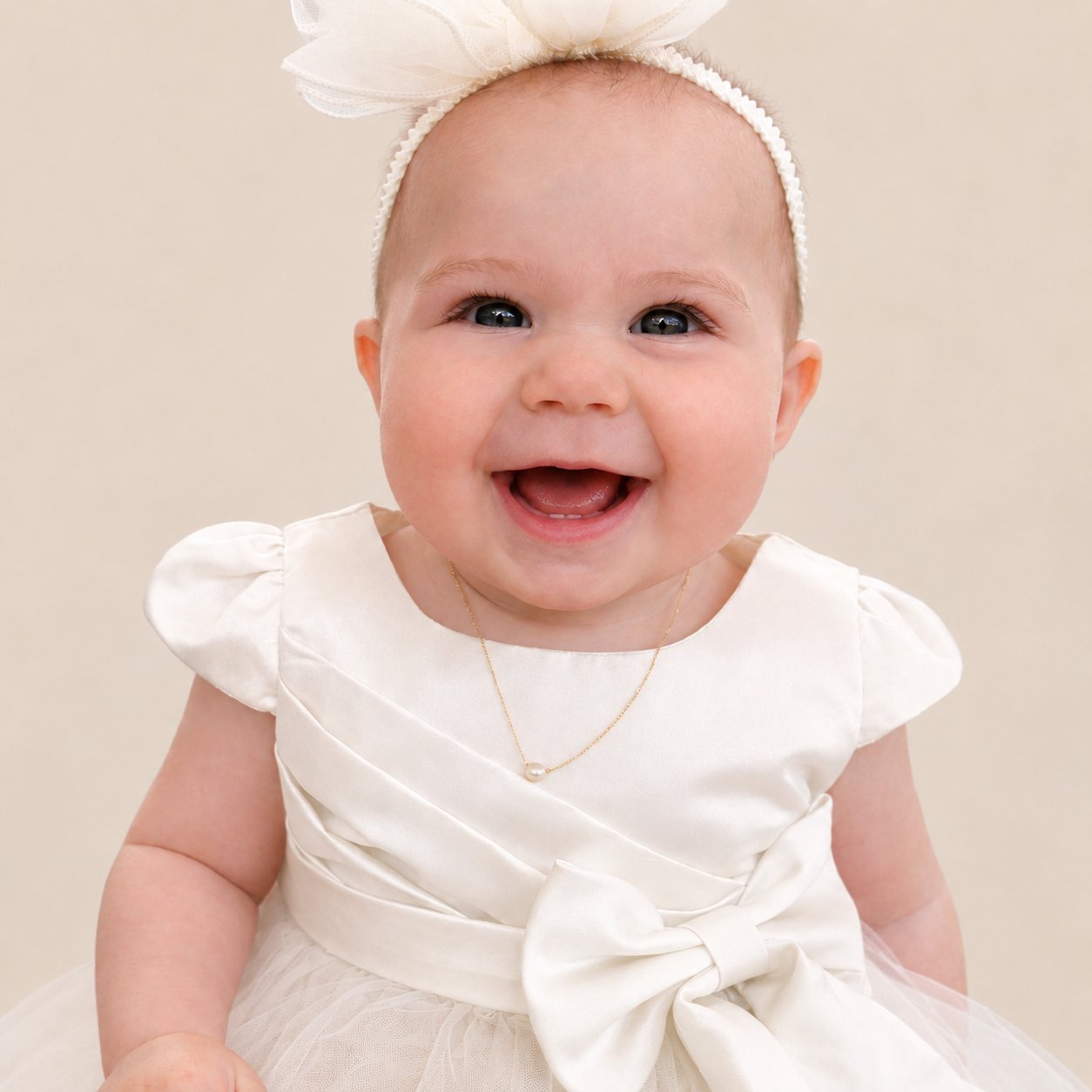 Baby in an ivory satin dress wearing her first pearl