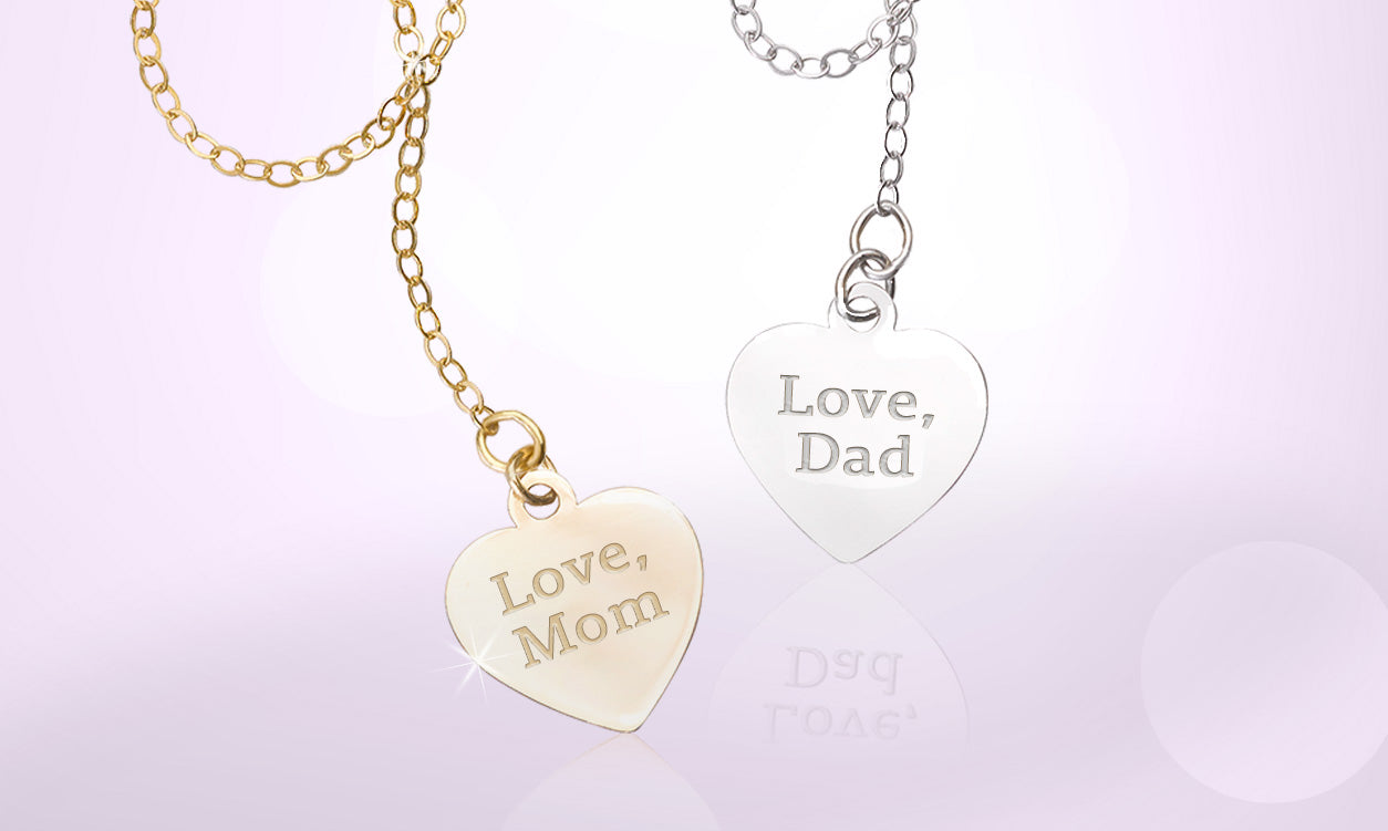 Engraved gold and silver heart charms reading Love, Mom and Love, Dad on soft lavender