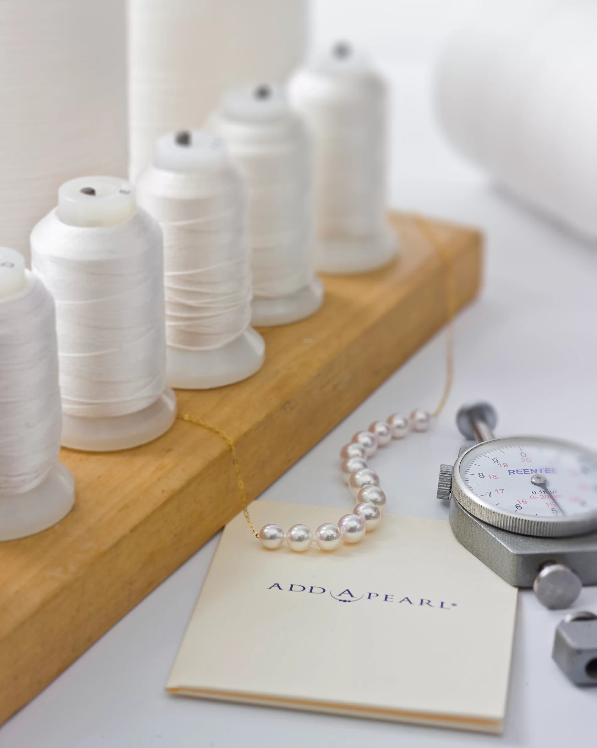 Pearl necklace with a measuring tool and spools of string